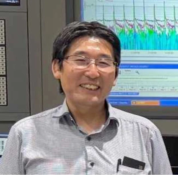 眼鏡をかけたアジア系の男性が笑顔でカメラを見ています