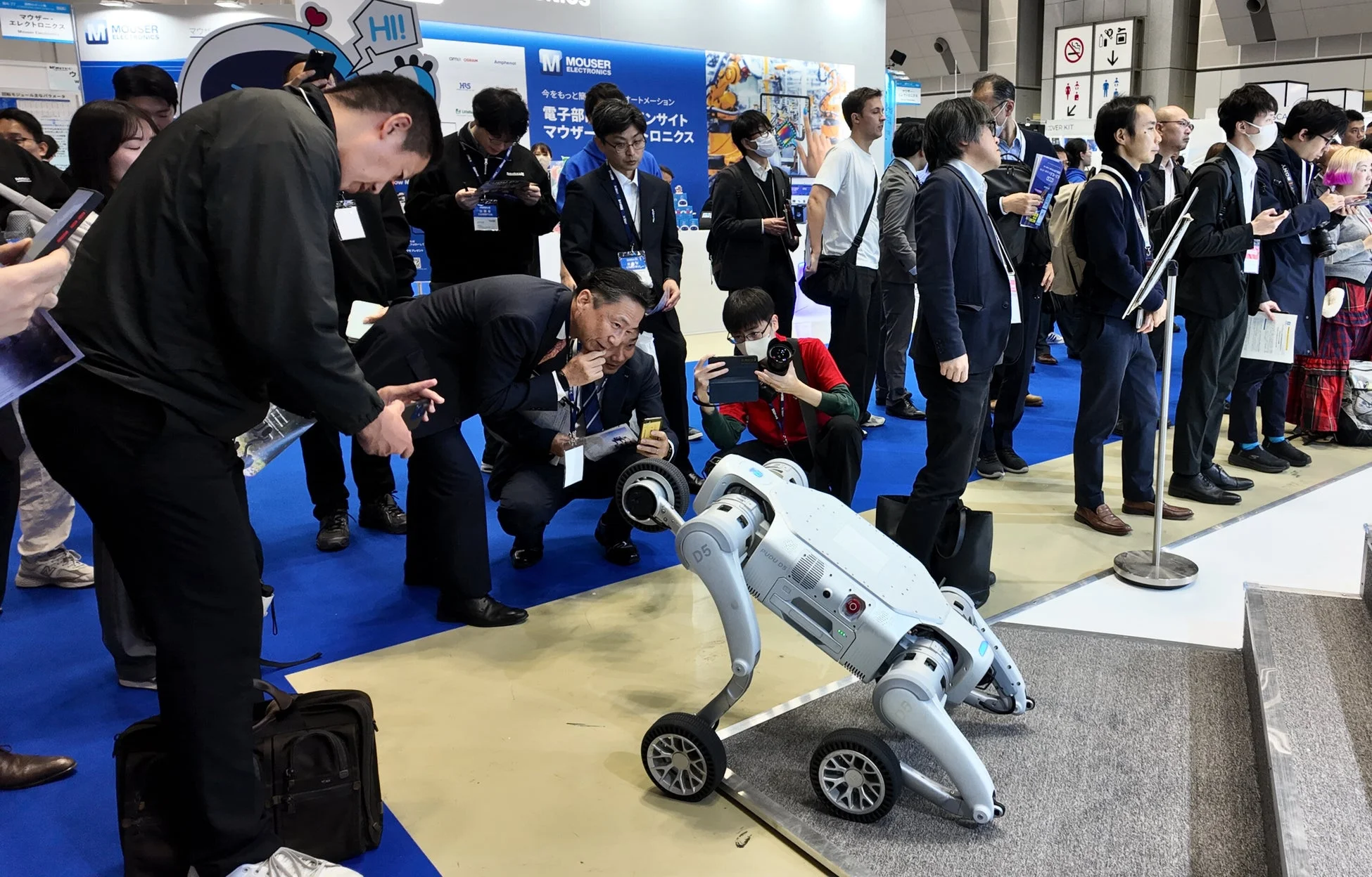 展示会で多くの人々がロボットを取り囲んでいる様子