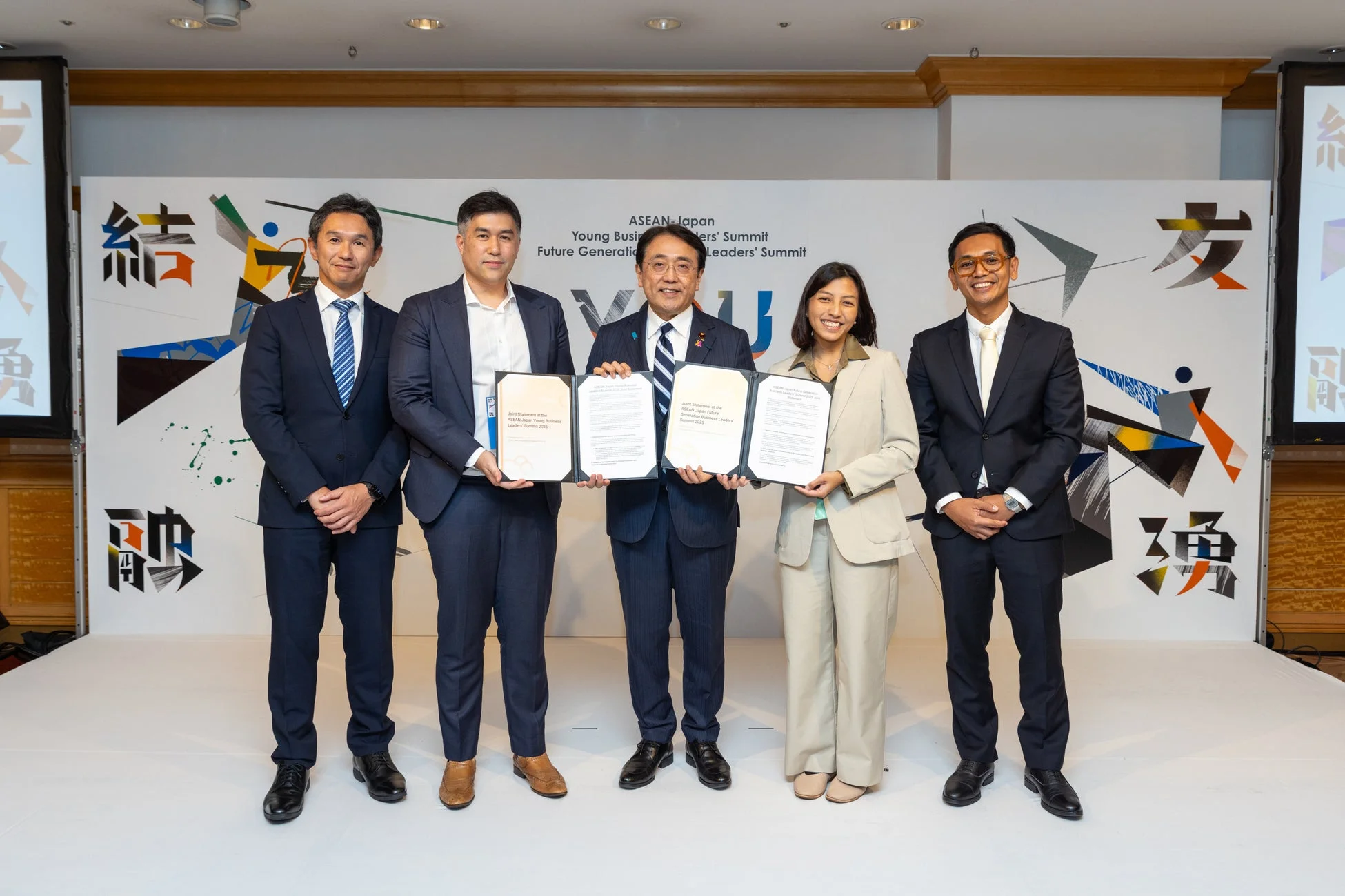 ASEANと日本の若手ビジネスリーダーズサミットにて、5人の参加者が共同声明の書類を手に記念撮影をしている様子