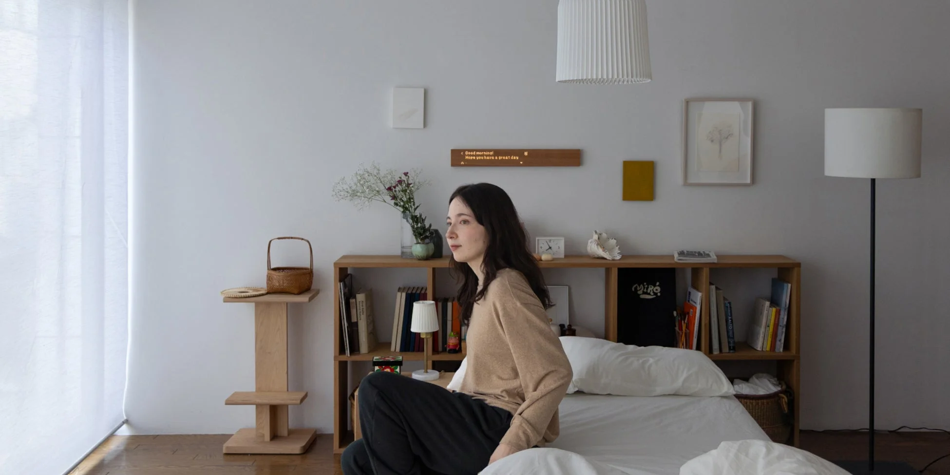 明るい寝室のベッドに座る女性