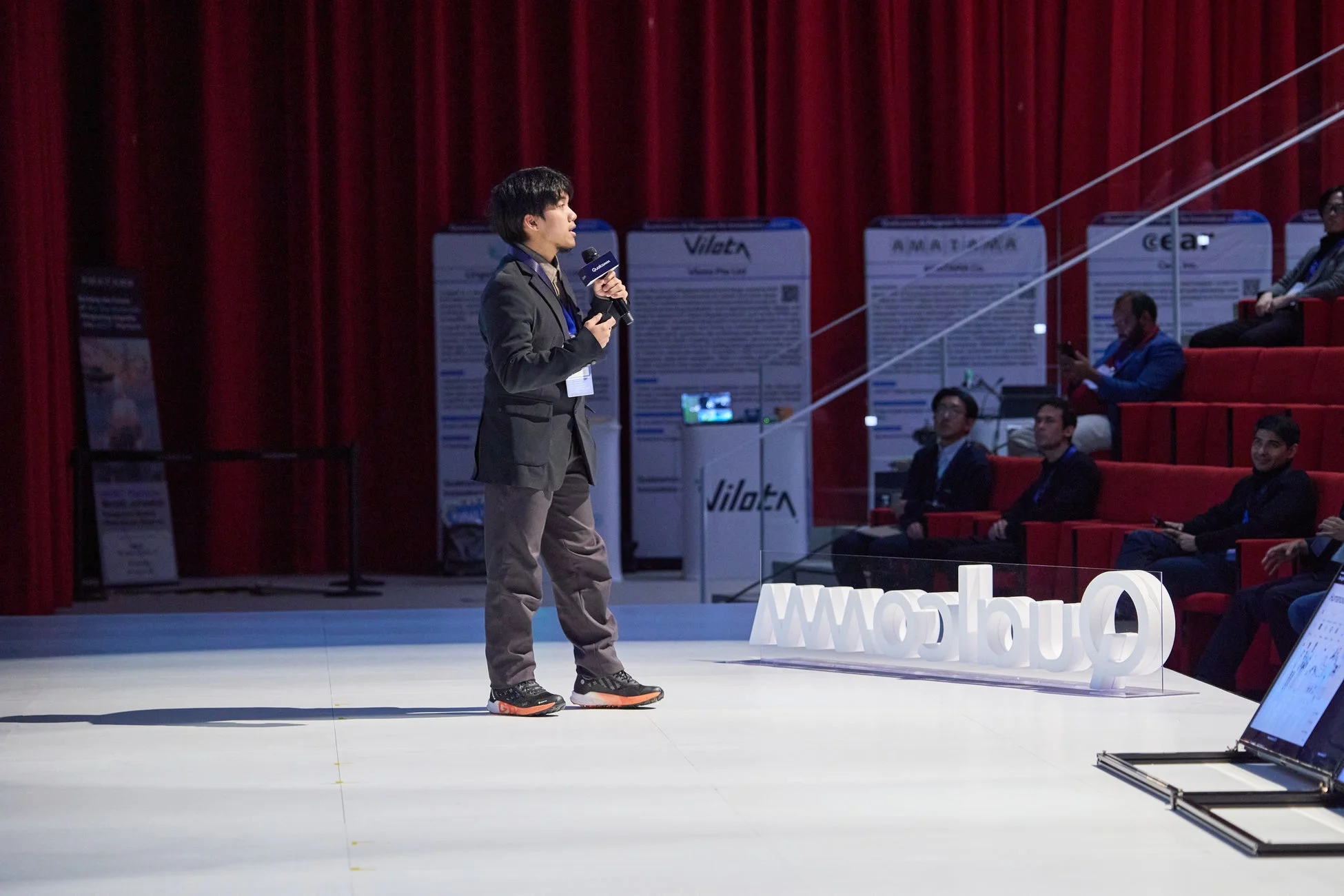 プレゼンテーションを行う男性とQualcommロゴ