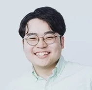 丸眼鏡をかけた東洋系の男性のポートレート