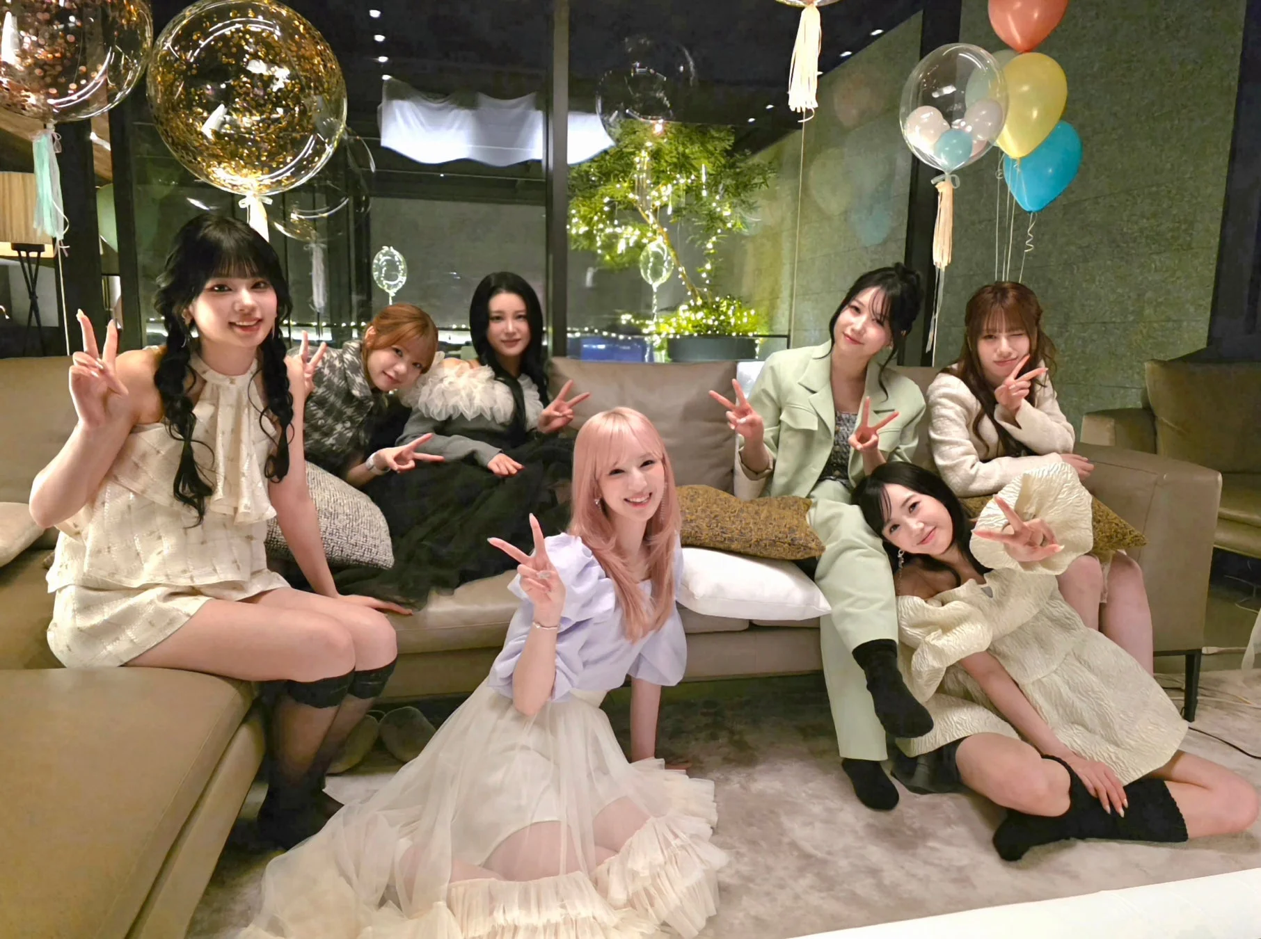 室内で8人の女性たちが集まり、笑顔でピースサインをしながら記念撮影をしている様子