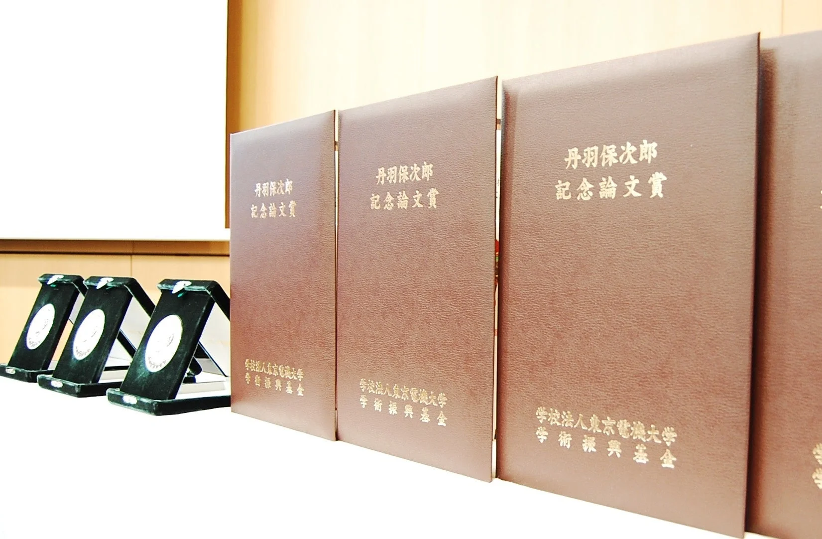 「丹羽保次郎 記念論文賞」と「学校法人東京電機大学 学術振興基金」と書かれた表彰状のようなファイルとメダル