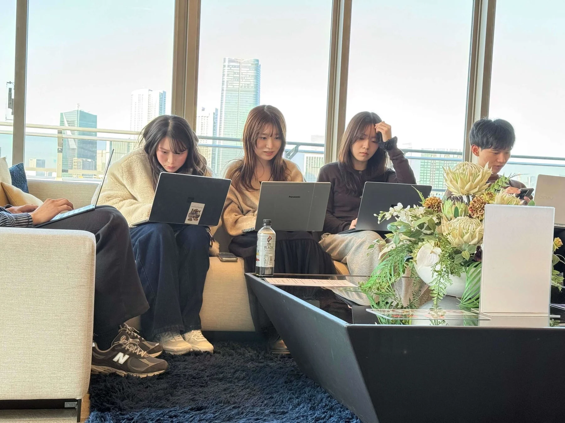 ソファでPC作業をする若者たち