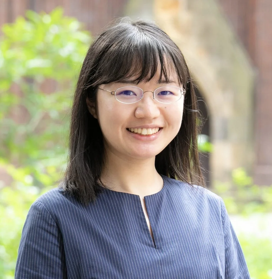 屋外で撮影された、眼鏡をかけたアジア系の若い女性のポートレート