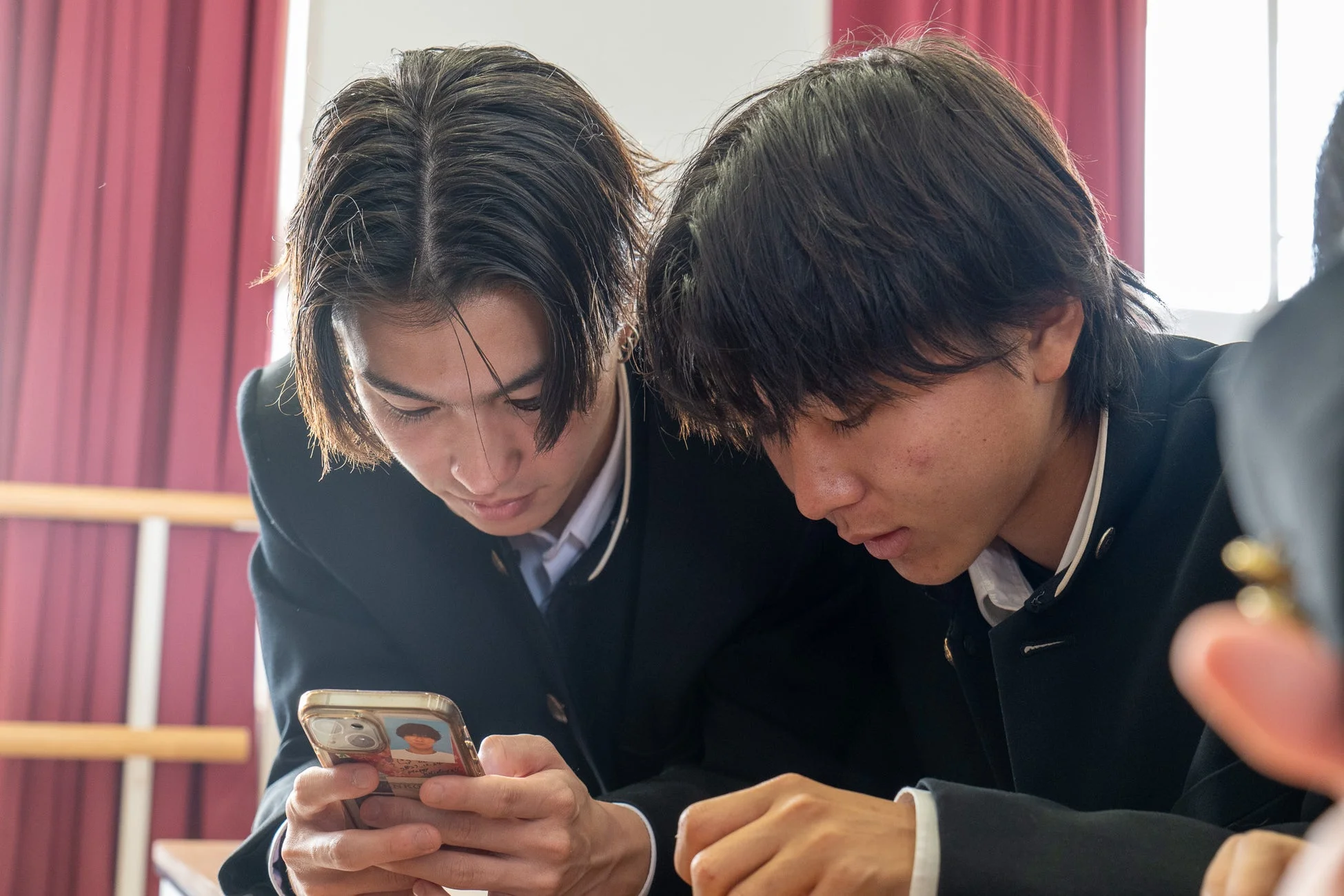 スマートフォンを覗き込む学生