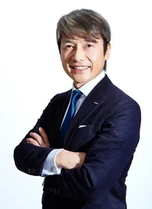 紺色のスーツと青いネクタイを着用し、腕を組んで笑顔を見せる中年のビジネスマンのポートレート写真