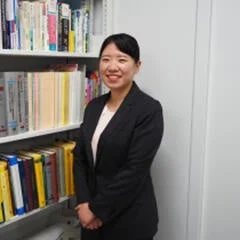 女性が笑顔で本棚の前