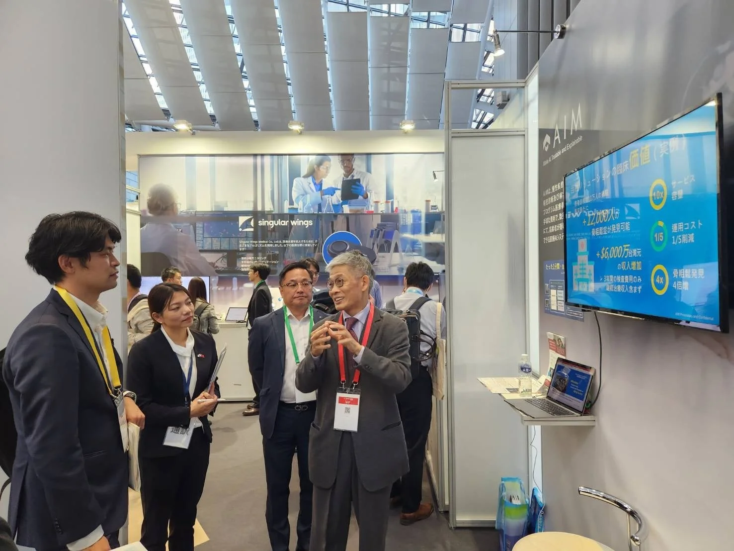 展示会ブースで医療AIソリューションについて説明を受ける参加者