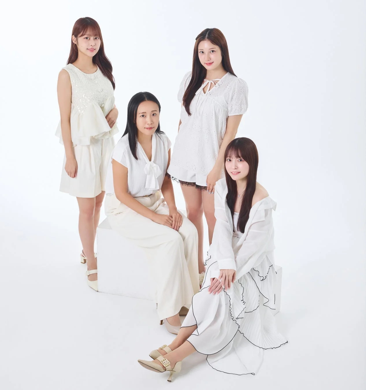 白い衣装を身につけた4人の女性が白い背景のスタジオでポーズをとっている集合写真