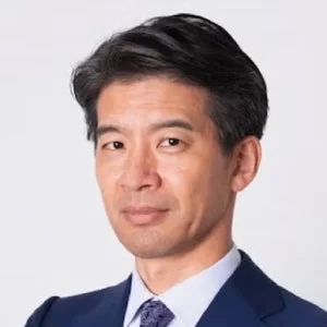 スーツを着たアジア系の男性の顔のアップ。真剣な表情でカメラを見つめており、ビジネスシーンでの使用に適したポートレート写真です。